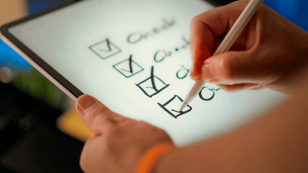 Person ticking off a checklist on a tablet using an Apple Pencil, representing a structured approach to evaluating and hiring a digital agency